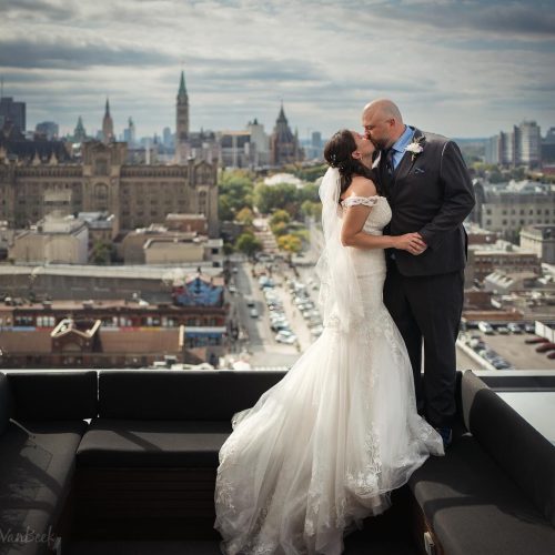 Bridge & Groom, kissing on the rooftop of the Andaz Hotel, with the Byward Market and Parliament Hill beyond.